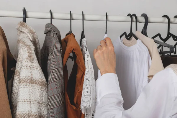 Kadın moda tasarımcısı giyinme odasındaki şık korkuluklardan kıyafet seçer. — Stok fotoğraf