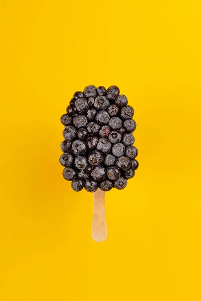 Glace créative à base de bleuets. Dessert estival rafraîchissant et lumineux sur fond jaune — Photo