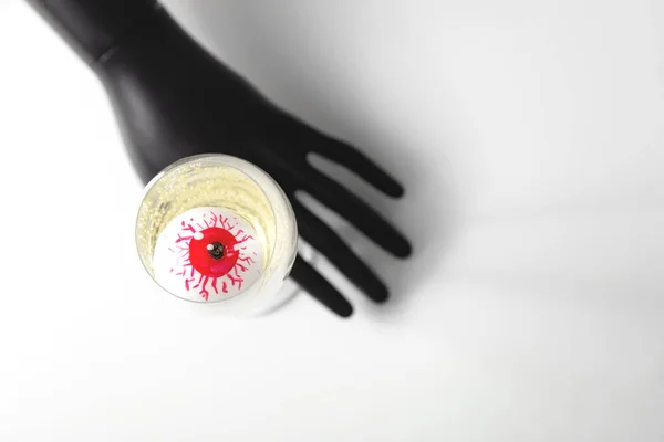 Piros szem egy pezsgős pohárban, fekete kézzel. Elegáns Halloween dekoráció. Őszi nyaralás koncepciója. — Stock Fotó