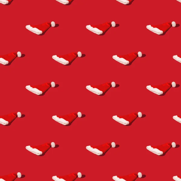 Bezproblémový vzor s čepicí Red Santa Claus na monohomickém pozadí. Minimalistická vánoční skladba. — Stock fotografie
