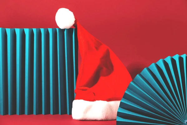 적색 배경에 바다 색깔의 기하학적 도형이 그려져 있는 미니멀리즘적 역반 풍경에 나오는 산타클로스 모자. — 스톡 사진