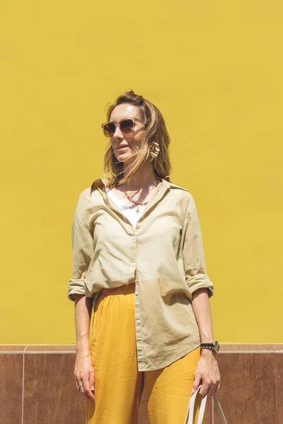 Femme élégante en tenue jaune contre le mur de couleur vive — Photo