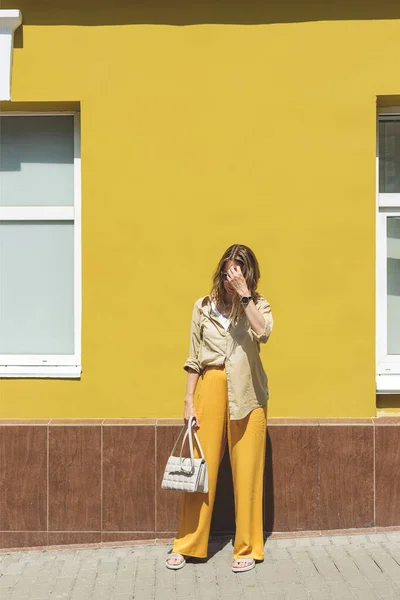 Femme élégante en tenue jaune contre le mur de couleur vive — Photo
