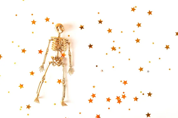 Esqueleto dourado em um fundo de Halloween leve com estrelas. Conceito minimalista de Halloween. — Fotografia de Stock