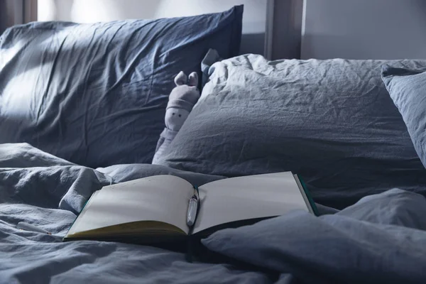 Відкритий щоденник для написання на ліжку з синім текстилем на місячному світлі. Вечірні ритуали для психічного здоров'я . — стокове фото