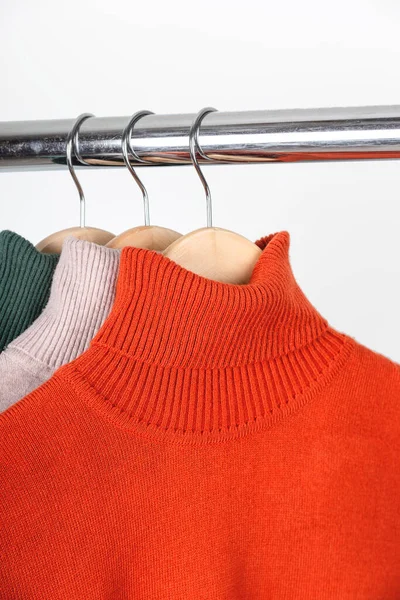 Temel sonbahar kadınlarının gardırop konsepti. Boş balıkçı yaka kazaklar elbise askısında. Parlak turuncu, yuvarlak yakalı, bej ve yeşil.. — Stok fotoğraf