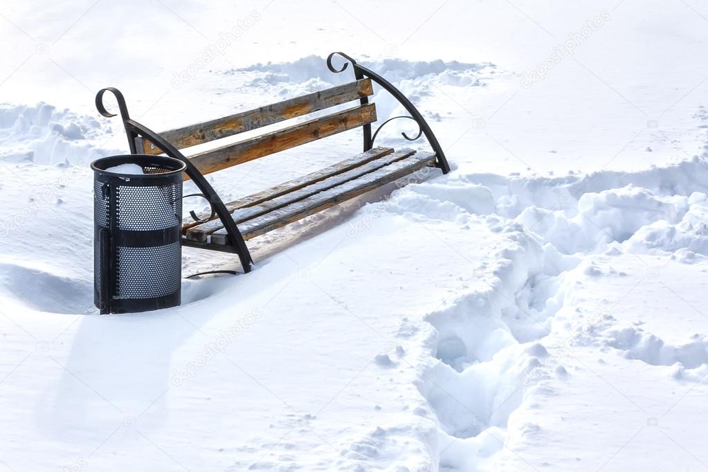 Lonely bench in winter snow covered park 