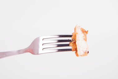 Domuz pirzolası beyaz zemin üzerine çatal üzerinde (hamur ve ekmek kırıntıları kaplı) parça