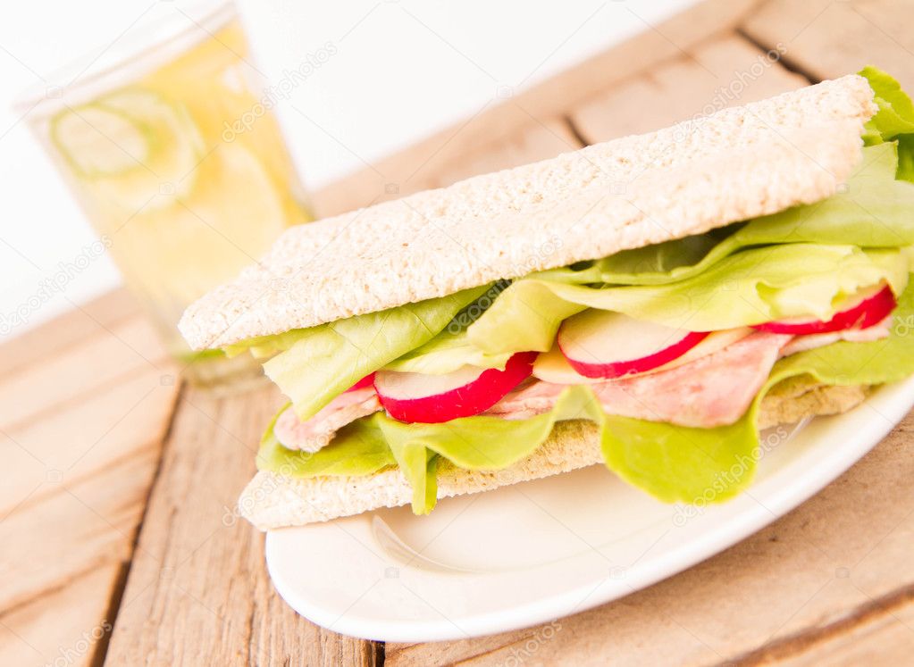 Crispbread sandwich with headcheese, cheese, radish and lettuce and a glass of lemonade