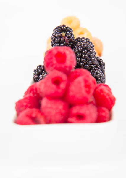 Raspberries and blackberries: bowls of fruit on white background