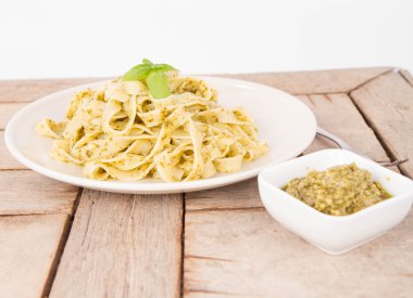 Ahşap arka plan üzerinde Fesleğenli tagliatelle pesto ile dekore edilmiş