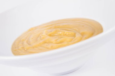 Beyaz arka planda bir tabakta balkabağı çorbası