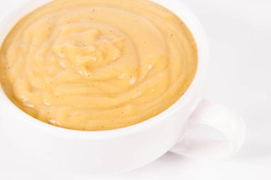 Beyaz arka planda bir kasede balkabağı çorbası