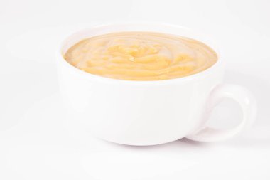 Beyaz arka planda bir kasede balkabağı çorbası