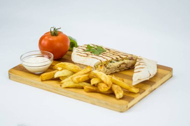 Shawarma sandwich, fresh roll in lavash with French fries. Kebab served on wooden board.