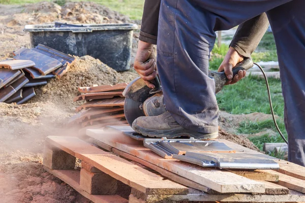 Arbeiter schneidet mit einer Handkreissäge einen Dachziegel — Stockfoto