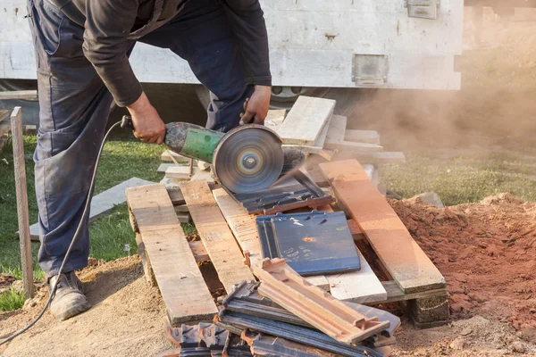 Worker using a hand circular saw to cut a roof-tile — Stock Photo, Image