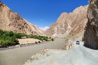 Pamir otoyolu M41 uluslararası karayolu veya Pamirskij trakt ve araba. Panj Nehri ve Pamir Dağları. Panj, Amu Darya nehrinin üst kısmıdır. Panoramik manzara. Tacikistan ve Afganistan sınırı