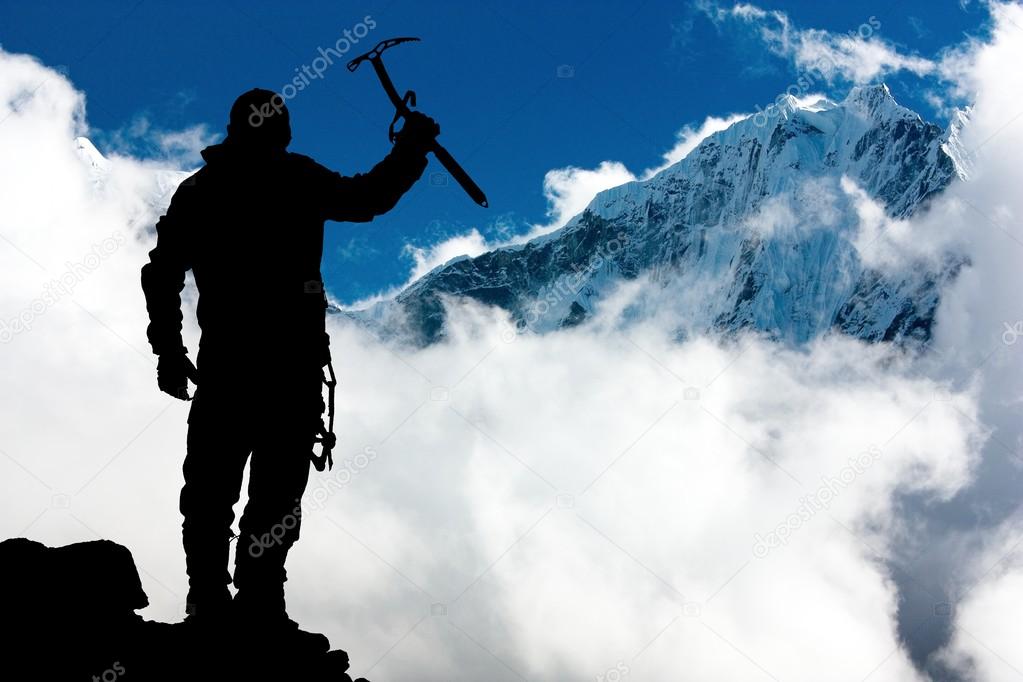Silhouette of man with ice axe in hand and mountains