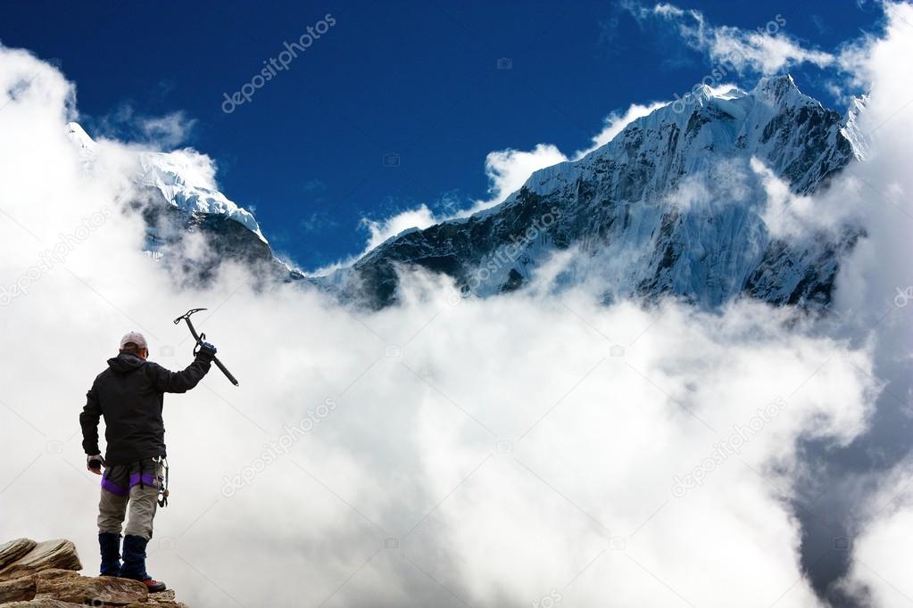 Silhouette of man with ice axe in hand and mountains