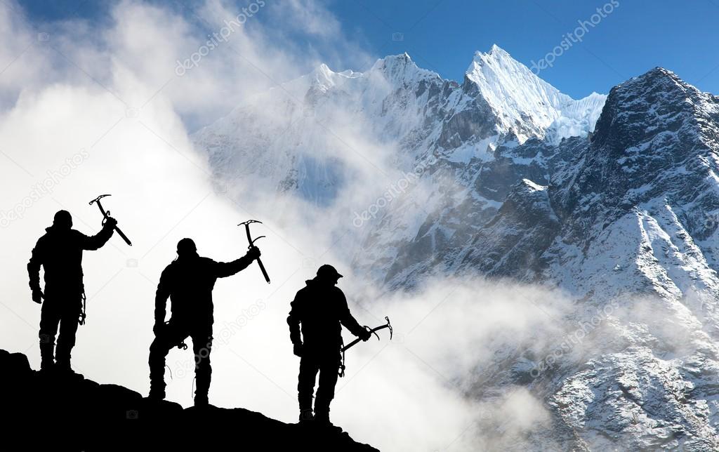 Silhouette of men with ice axe in hand and mountains