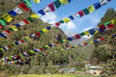 Prayer flags and a rope hanging suspension bridge full of tourists. Bridge over the Dudh Koshi river in Khumbu valley, between Lukla and Namche bazar on the way to Mount Everest base camp 
