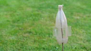 Yeşil bir çayırda dönen eski bir plastik şişeden yapılmış bir fırıldak. İnsanların olmadığı bir gelecek..