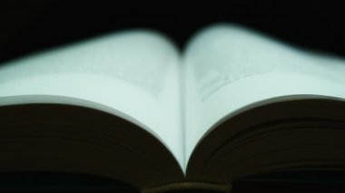 The pages of an open book are flipped over against a dark background. Close-up shooting