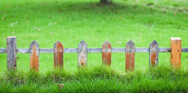 Cerca pequena velha no gramado verde no jardim — Fotografia de Stock