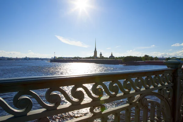 Troitsky Bridge, view of the Neva and the Peter and Paul Fortress, the rays through the iron fence. — Stock Photo, Image