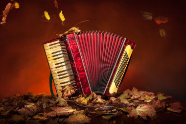Vintage accordion among the autumn leaves clipart