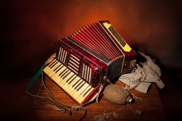 Accordéon vintage, fiole militaire sur la table en bois et fond rouge — Photo