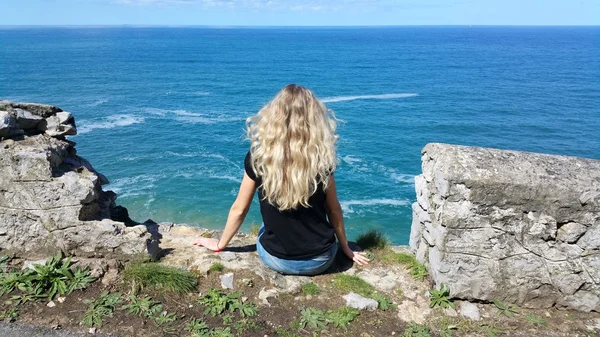 Blonde girl sitting back on the rock — Stock Photo, Image
