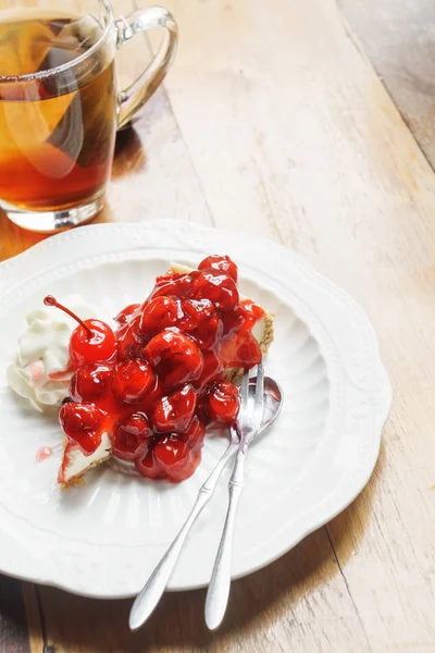 Bolo de queijo de cereja caseiro com chá de frutas na mesa de madeira — Fotografia de Stock
