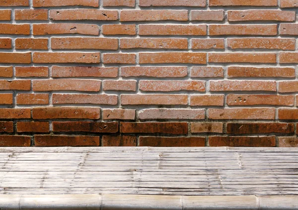 Mesa de mimbre de bambú en la pared de ladrillo naranja grunge — Foto de Stock