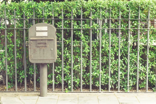 Винтажный ржавый стальной почтовый ящик перед металлическим забором и зеленый он — стоковое фото