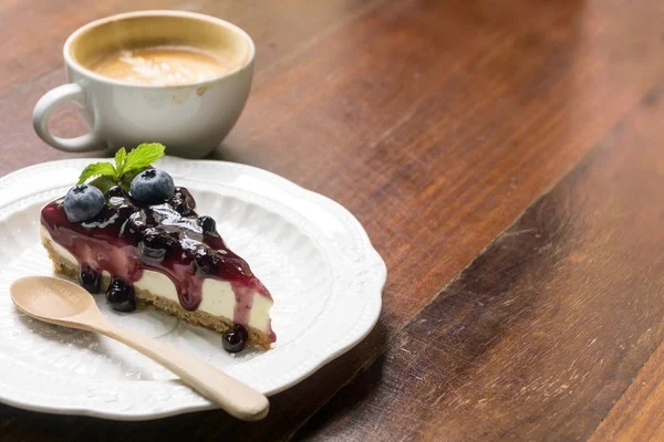 Blauwe bes cheese cake en koffie latte op houten bureau — Stockfoto