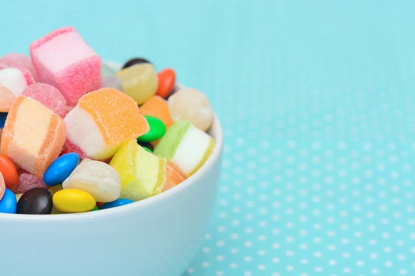 Geleia de doces coloridos na tigela na toalha de mesa azul ponto branco — Fotografia de Stock