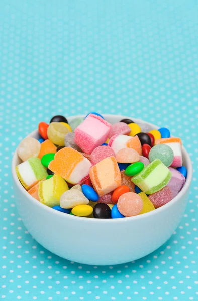 Geleia de doces coloridos na tigela na toalha de mesa azul ponto branco — Fotografia de Stock