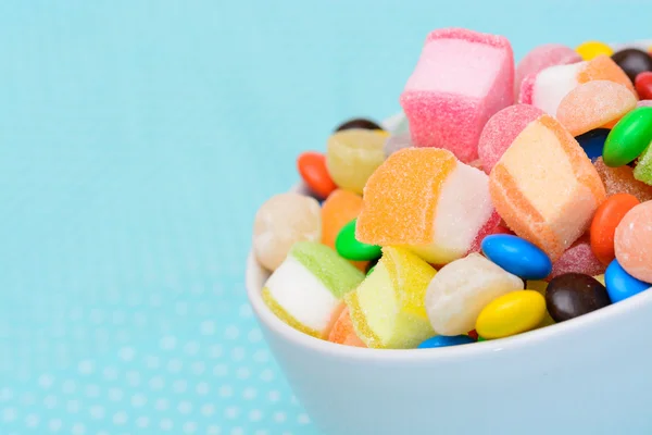 Geleia de doces coloridos na tigela na toalha de mesa azul ponto branco — Fotografia de Stock