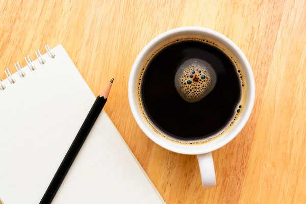 Café negro y bloc de notas en mesa de madera — Foto de Stock