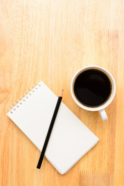 Black coffee and notepad on wooden table