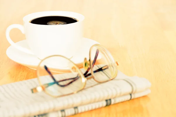 Vintage look of coffee and newspaper on wooden table — Stock Photo, Image