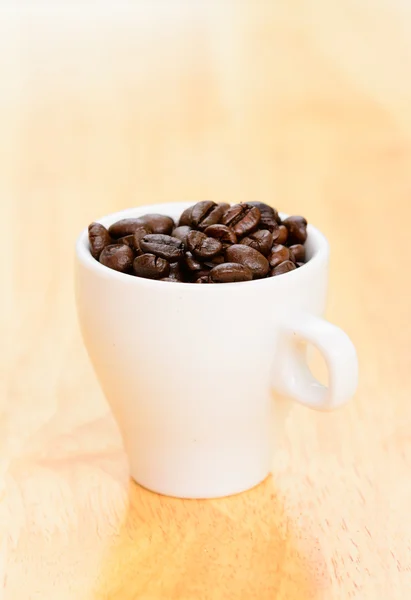 Xícara de grãos de café na mesa de madeira velha — Fotografia de Stock