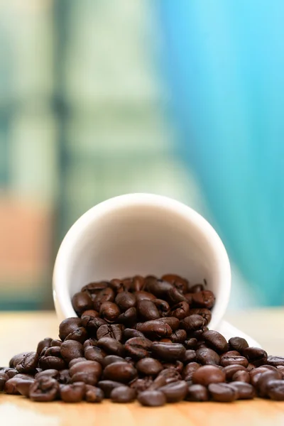 Xícara de grãos de café na mesa de madeira pela janela — Fotografia de Stock