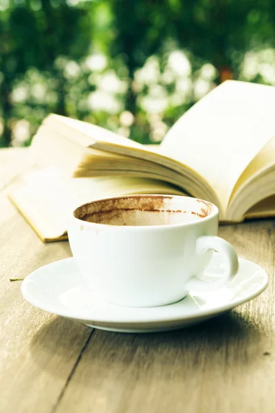 Coffee break and open book on wooden table in garden — Stock Photo, Image