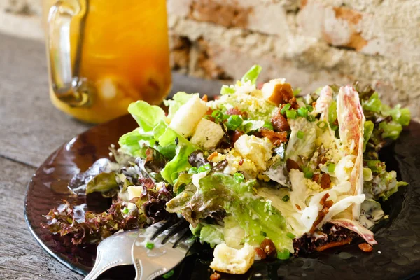 Caesar salad on grunge wooden table and brick wall — Stock Photo, Image