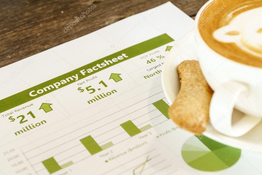 Drinking coffee while reading company financial fact sheet