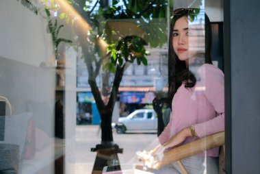 Kafenin penceresinden bakan genç bir kadın.