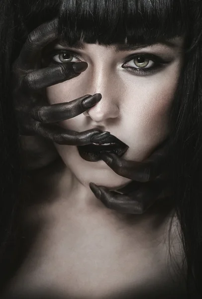 Woman with black demon hands on face — Stock Photo, Image